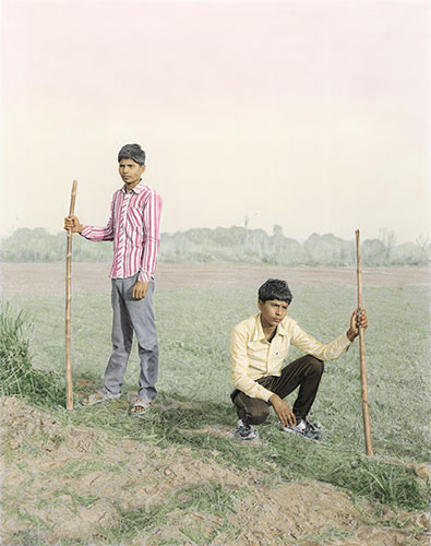 Photo de Vasantha Yogananthan de deux jeunes garçons tenant des batons dans un champ en Inde dans le cadre du festival Photographique Influences indiennes à Beaucouzé